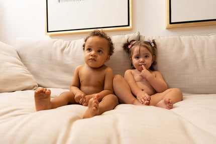 2 bebés sentados en un sillón usando únicamente su pañal Nunuū con cara de reflexión